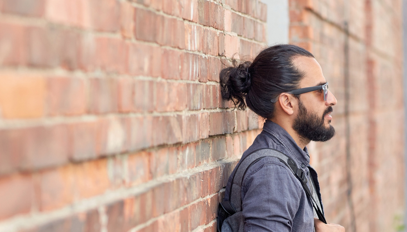 Ein Mann lehnt an einer Ziegelsteinmauer.